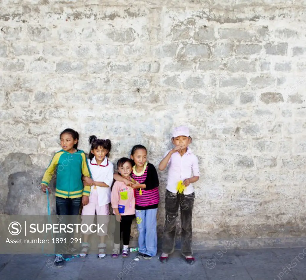 Children standing in front of a stone wall, Tibet,