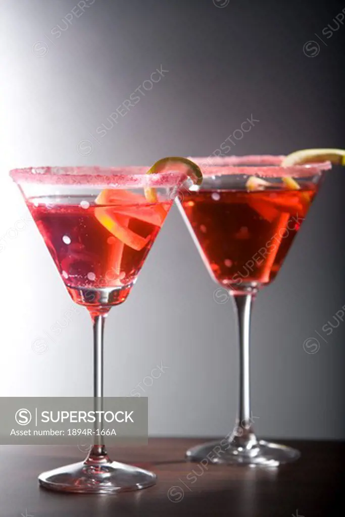 Two glasses of cocktail with lemon peels