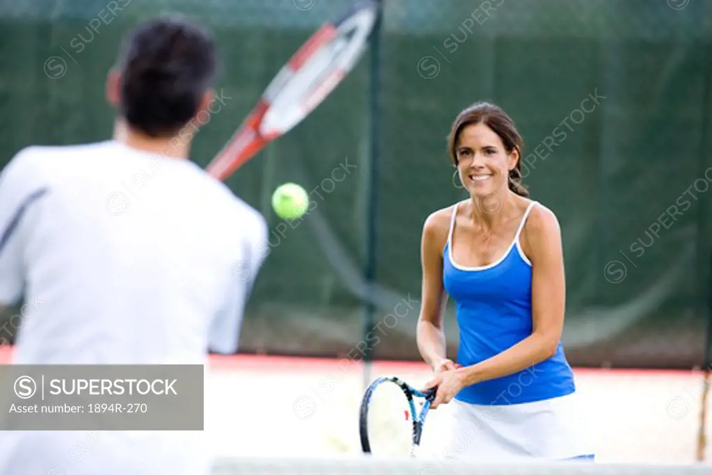 Young couple playing tennis in the court of a tourist resort