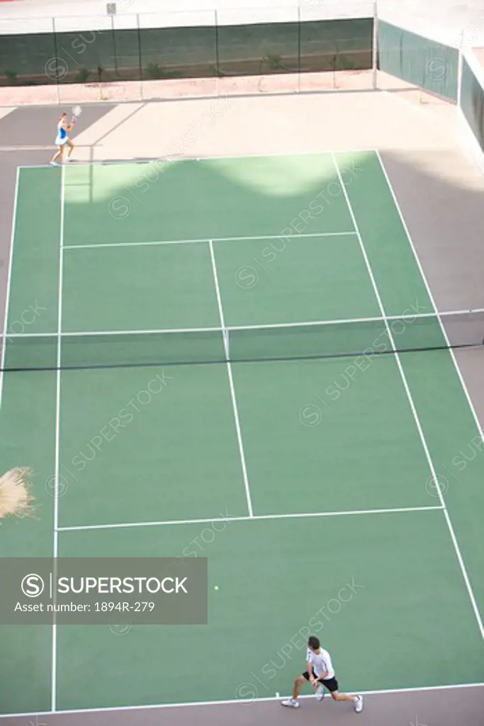 Young couple playing tennis in the court of a tourist resort