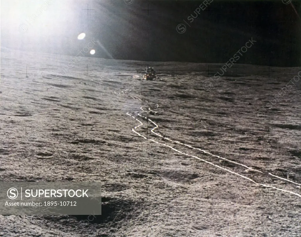 The lunar lander is photographed against a brilliant sun glare. The bright trail in the lunar soil has been left by the two-wheeled MET (Modularized E...