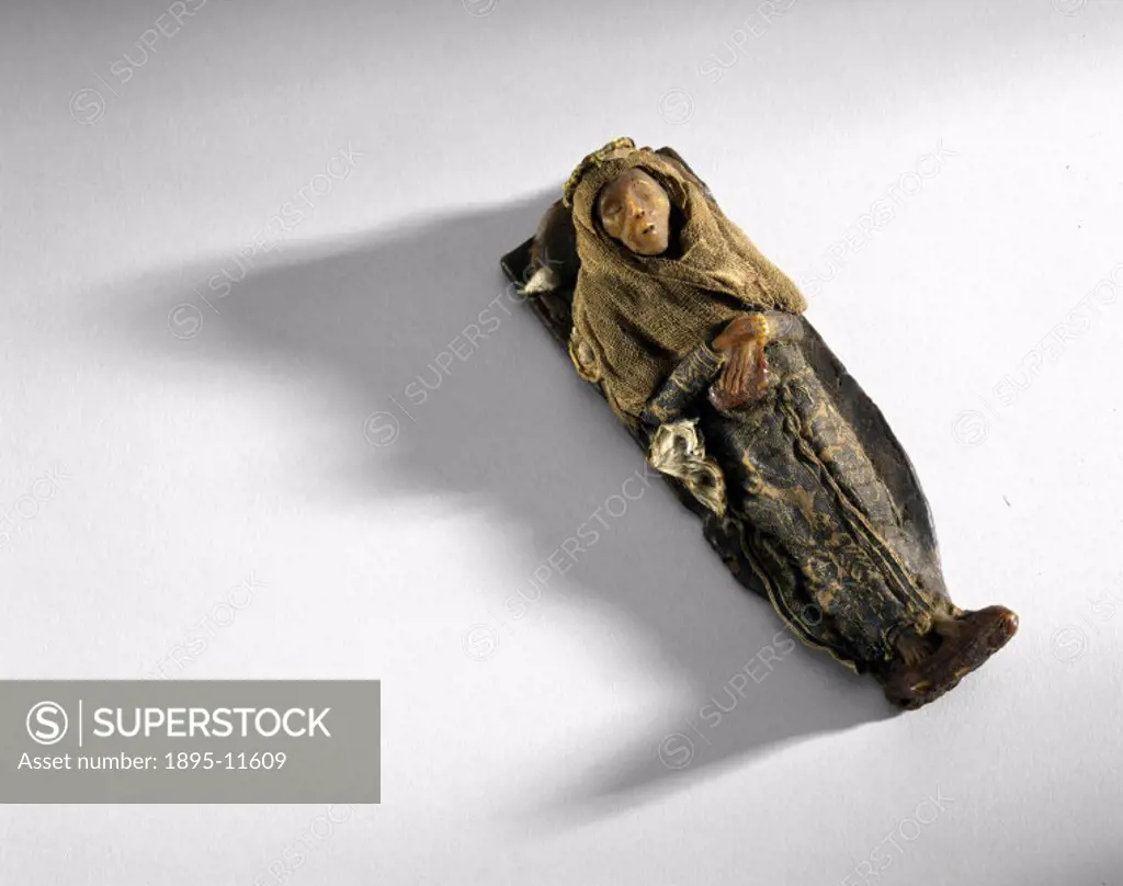 This wax model, on a wooden base, is of a mummy in grave clothes.
