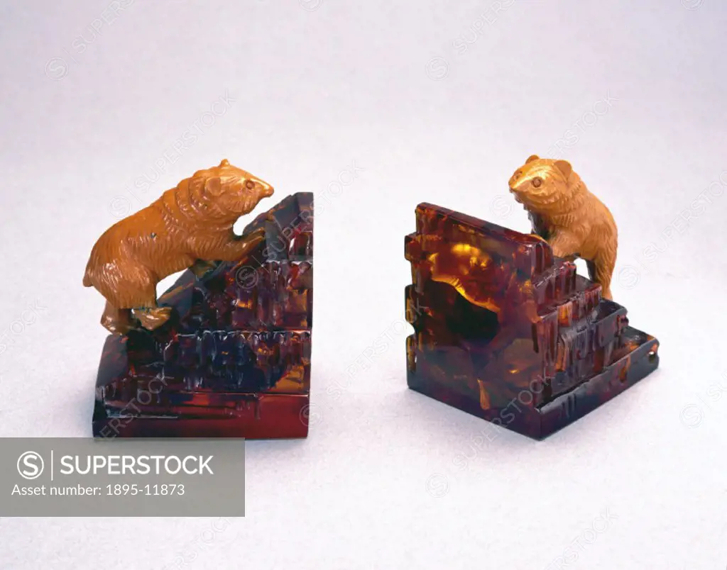 Cast book-ends of transparent amber cast phenolic, surmounted by bears of orange urea formaldehyde. By 1928, phenolic resins could be produced at lowe...