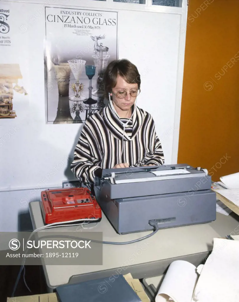 Female office worker typing from a recording of speech.