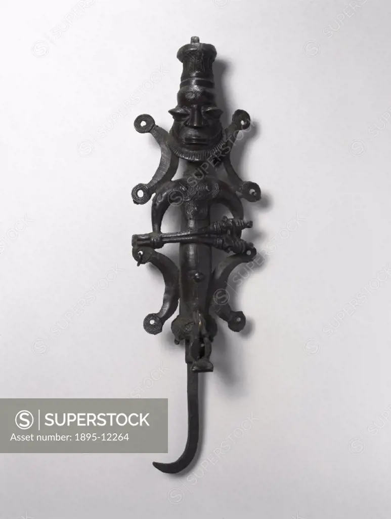 This staff is an Ogboni sceptre. It has a hooked grip,a loop on top of the head, and a male figure holding a pair of figurated spikes. The Ogboni (Osu...