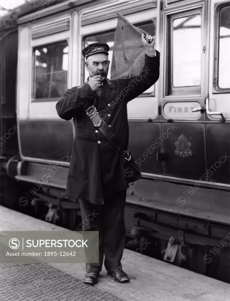 A guard waves his flag to give the ´right away´ signal for the departure of a train from Holyhead Station. London and North Western Railway.