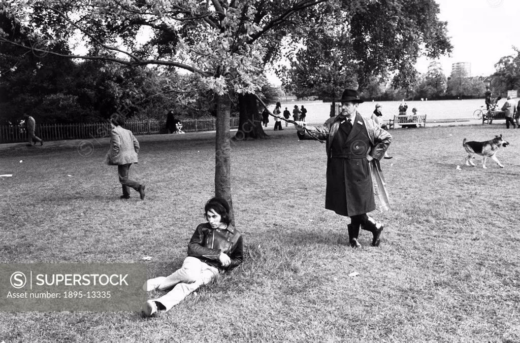 Young man leaning against a tree, Regent´s Park, London, 1969. A middle_aged park_keeper is holding a branch of the tree. With pursed lips, he seems i...