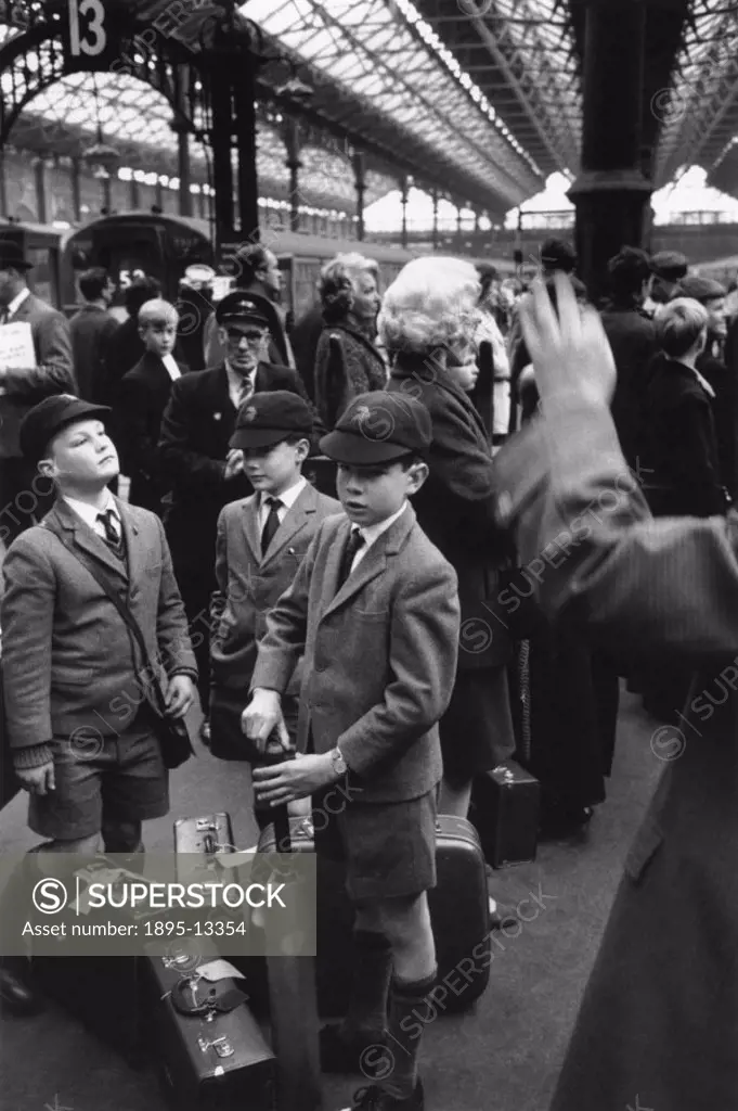 Three young schoolboys waiting with their luggage on a platform at Victoria railway station in London before returning to boarding school. Photo taken...