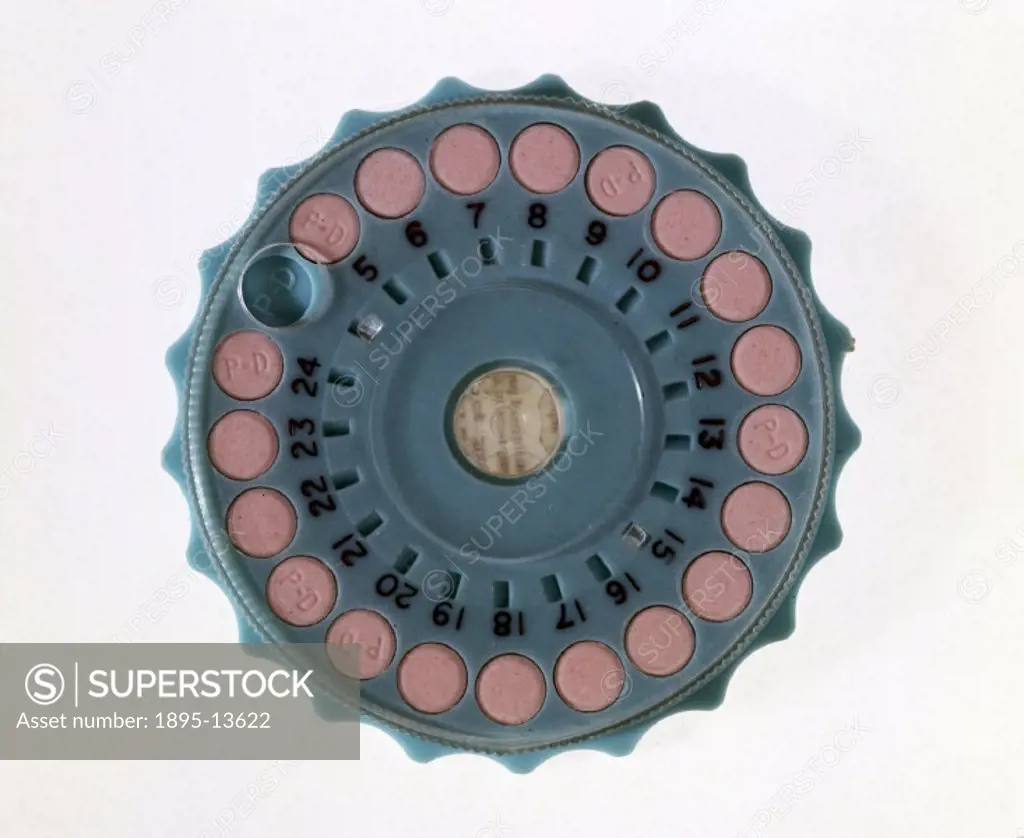 Pink contraceptive pills (marked ´PD´) in a circular blue plastic dispenser. The top transparent plastic disc could be rotated, allowing one pill to b...