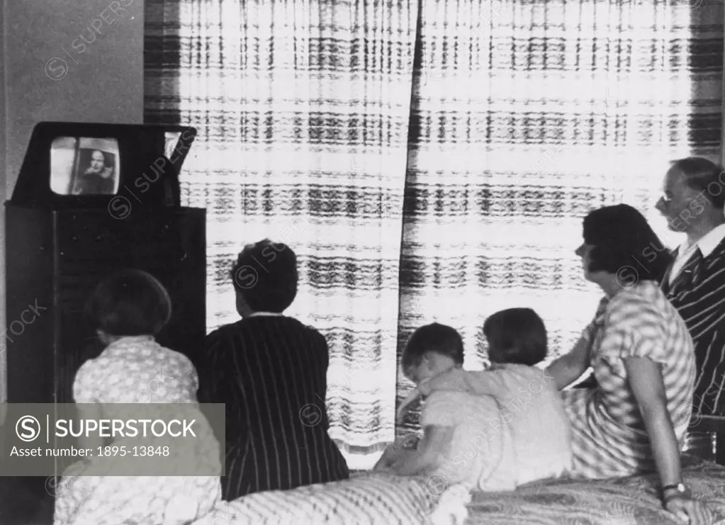 A family watching a television broadcast, c 1930s.Photograph showing a family watching a television programme on a mirror lid television. When switche...