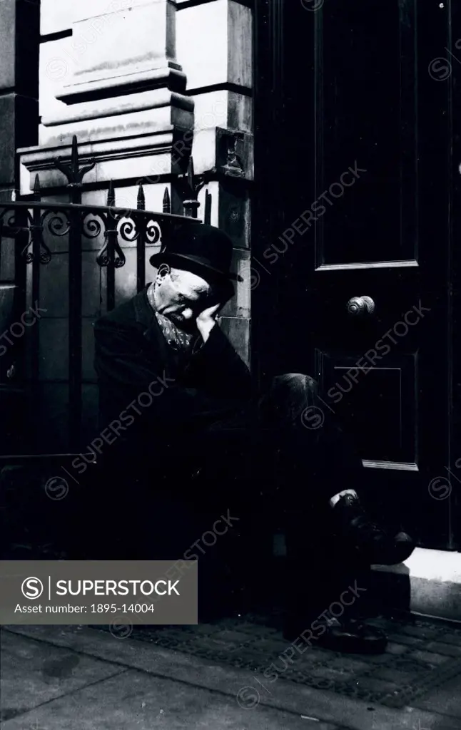 Sleeping vagrant sitting on a box in a doorway, c 1900.
