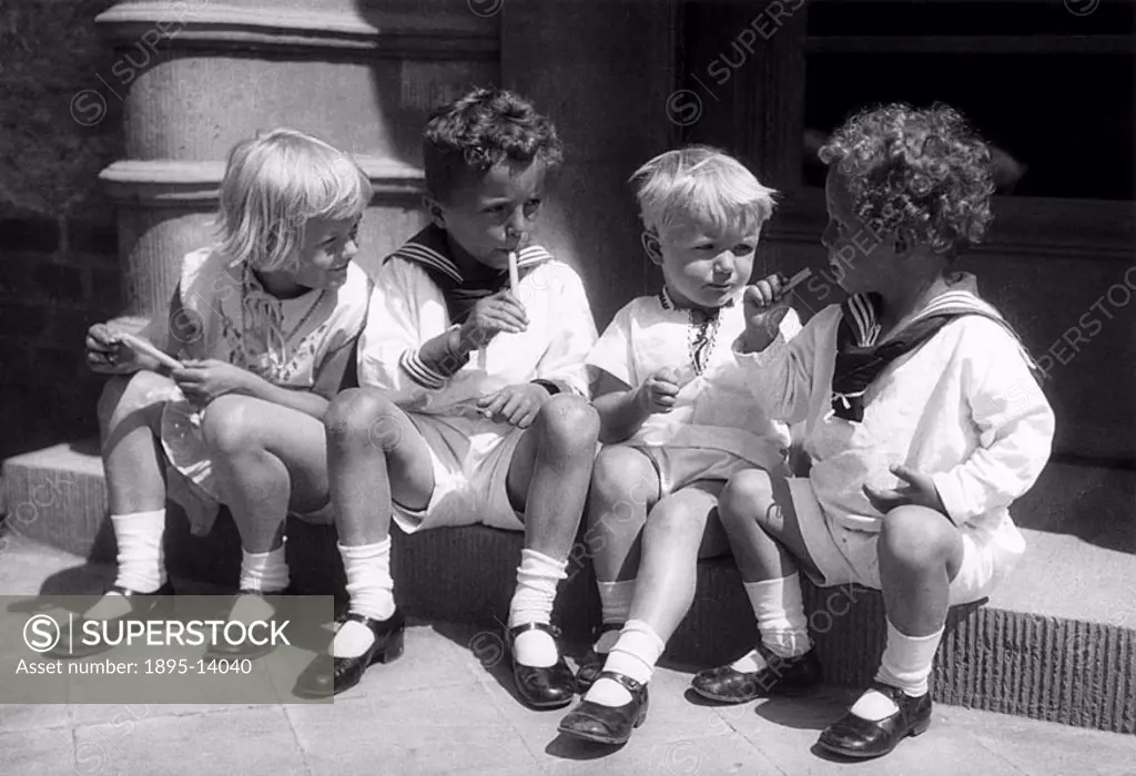 Four children sitting on a step eating ice-lollies.