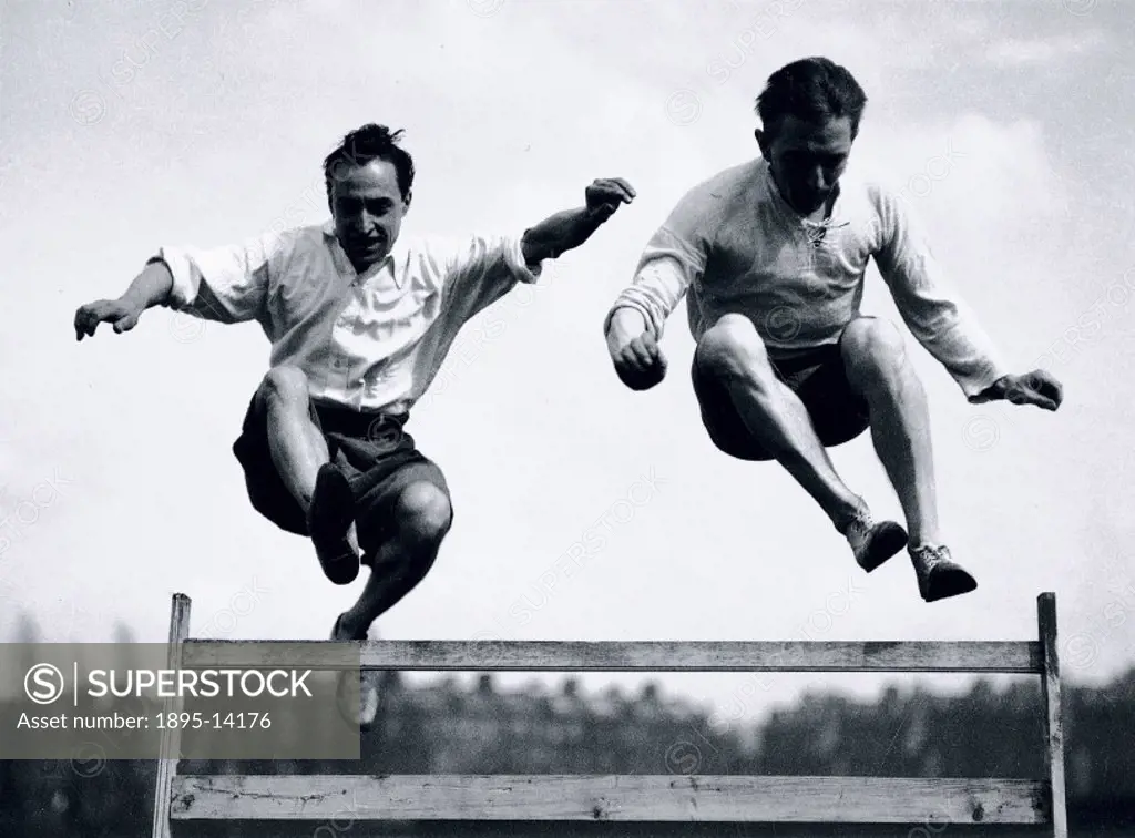 Two men jumping a steeplechase hurdle, c 1920s.