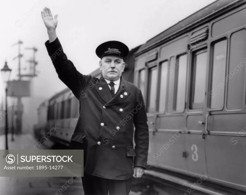 London Midland & Scottish Railway foreman giving the hand signal for the train departure, at Chorley Station, Lancashire.