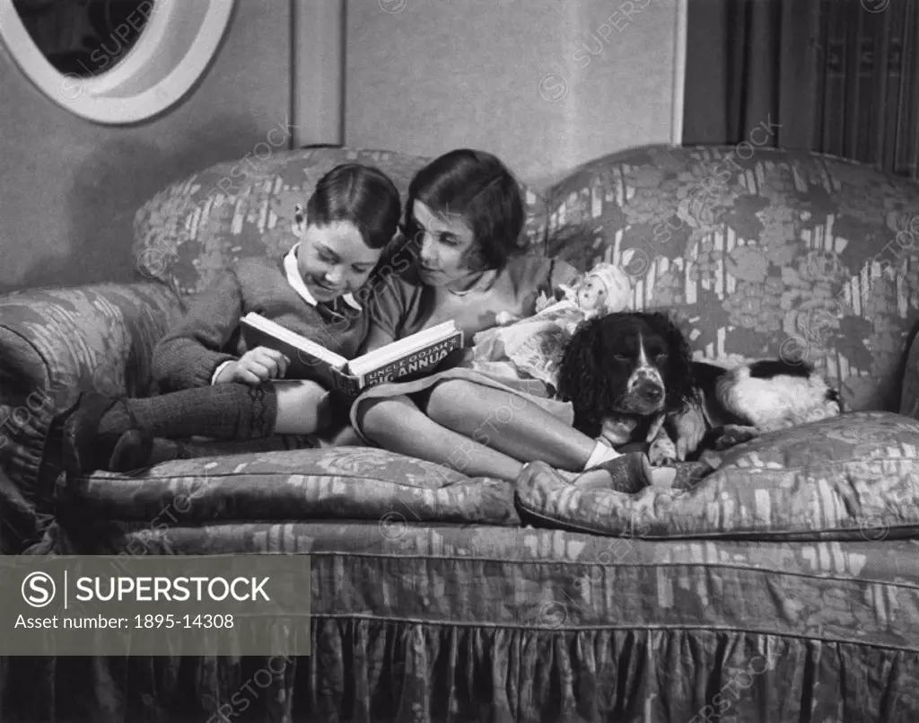 Two children on a settee reading ´Uncle Oojah´s Big Annual´, c 1930s.