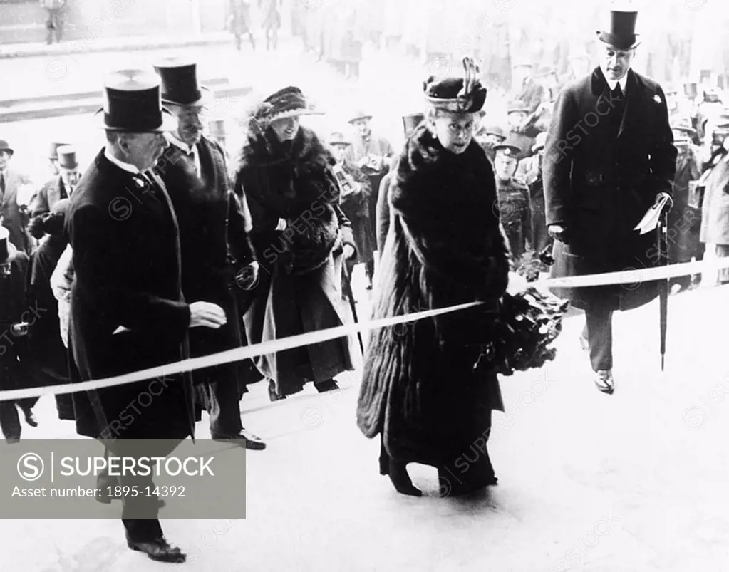 Queen Mary, watched by senior London & South Western Railway officials and holding a bouquet of red roses presented to her, cuts the silken cord to op...