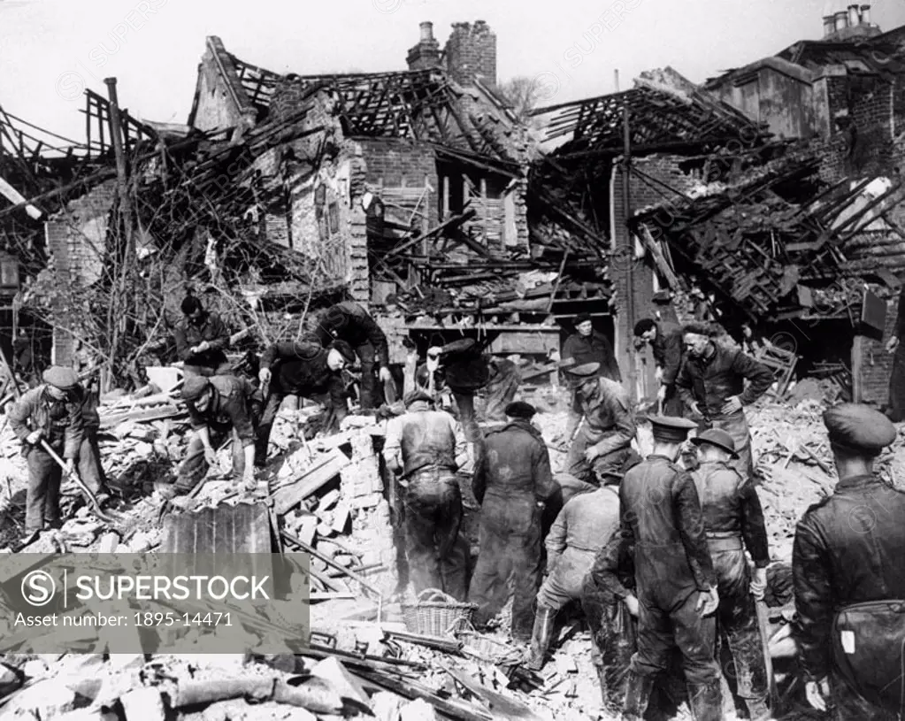 Rescue workers searching the wreckage of houses for victims during the Blitz. Photograph by F Greaves.