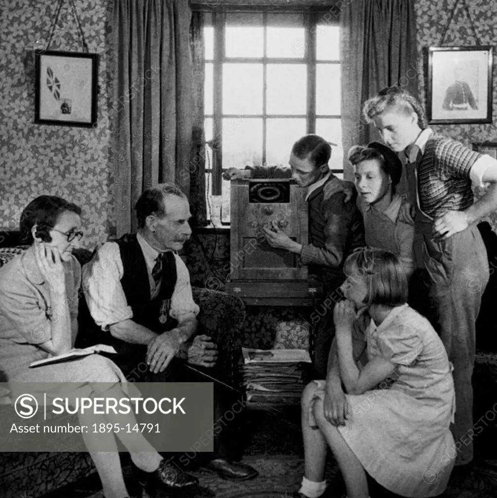 Family listening to a speech by Winston Churchill, 19 May 1945. Mr and Mrs Cooper and family tuning in their wireless to listen to a speech by Prime M...