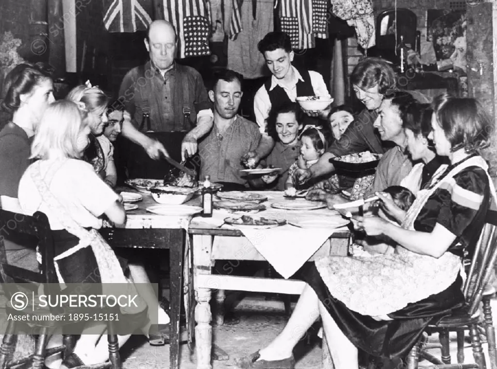 ´The families of Parish Brooks sitting around the table eating their Sunday dinner. The families lived under a lean-top shelter behind their blitzed h...