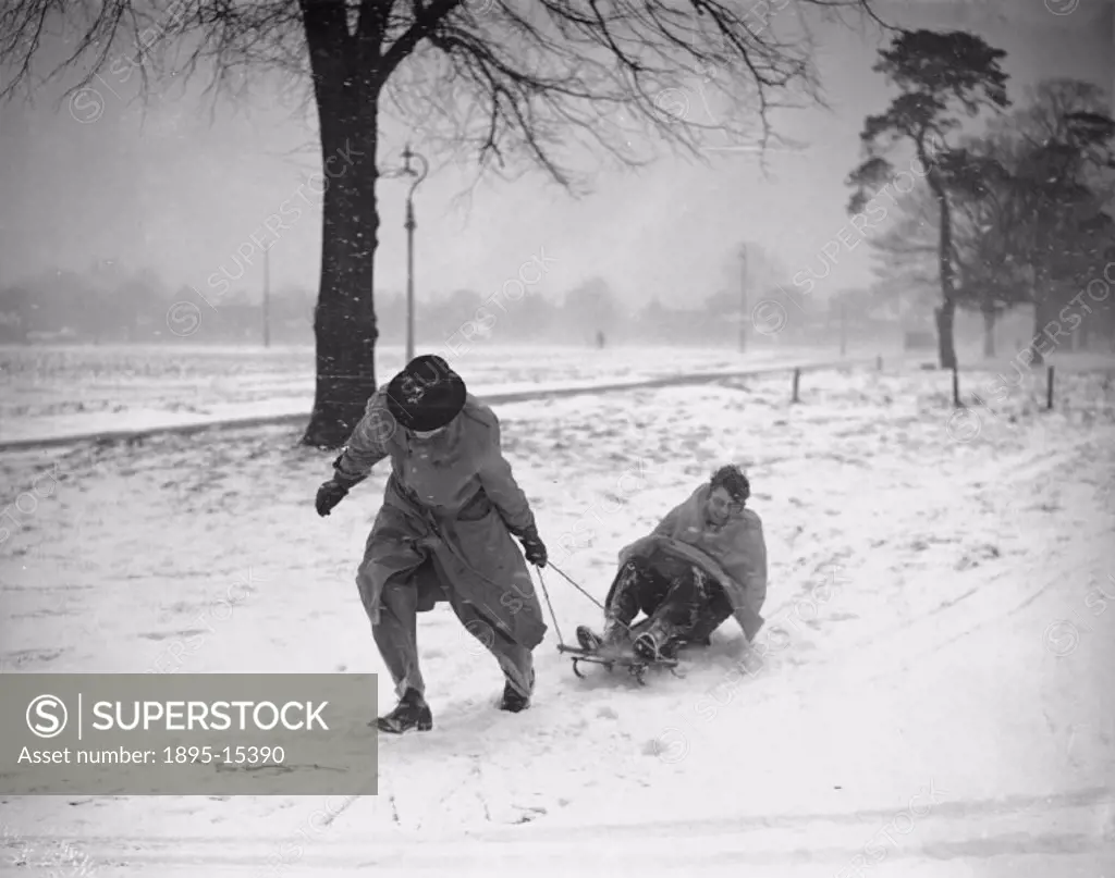 Man pulling boy on sled on Wimbledon Common, London, 19 December 1938.
