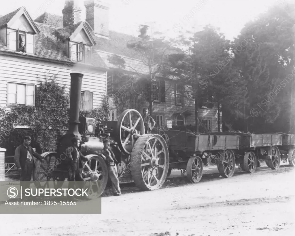 A steam traction engine with wagons, surrounded by engineers. From a wet plate negative by Hodges.