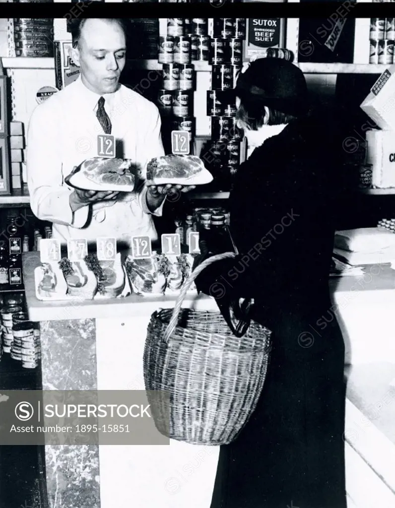 Woman choosing a side of bacon at the grocers, 15 April 1937.