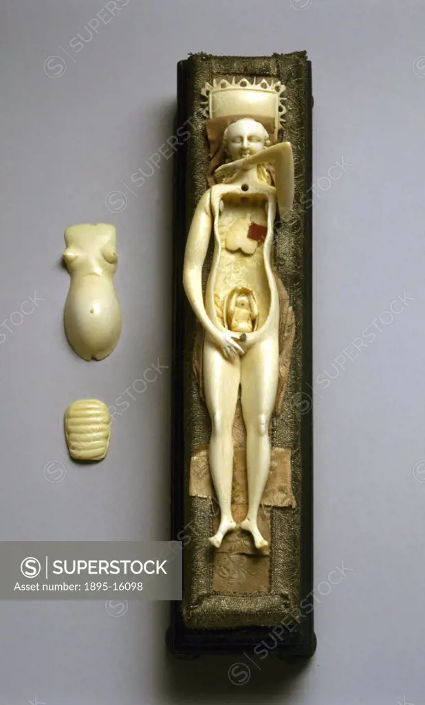 This ivory figure of a pregnant female is lying on a wood and cloth bed and has an ivory pillow under its head. The figure has some removable organs a...