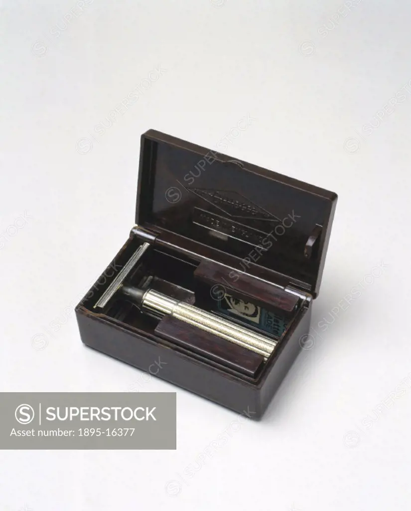 Rectangular box of walnut phenolic (bakelite) with hinged lid, containing a Gillette safety razor and two blade containers, one holding two packets of...