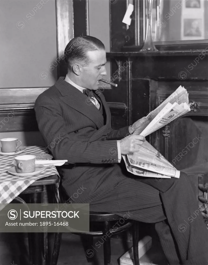 A man with slicked-back hair and wearing a wide-lapel suit sits reading a newpaper and smoking a cigar. The table next to him is laid with teacups. Pi...