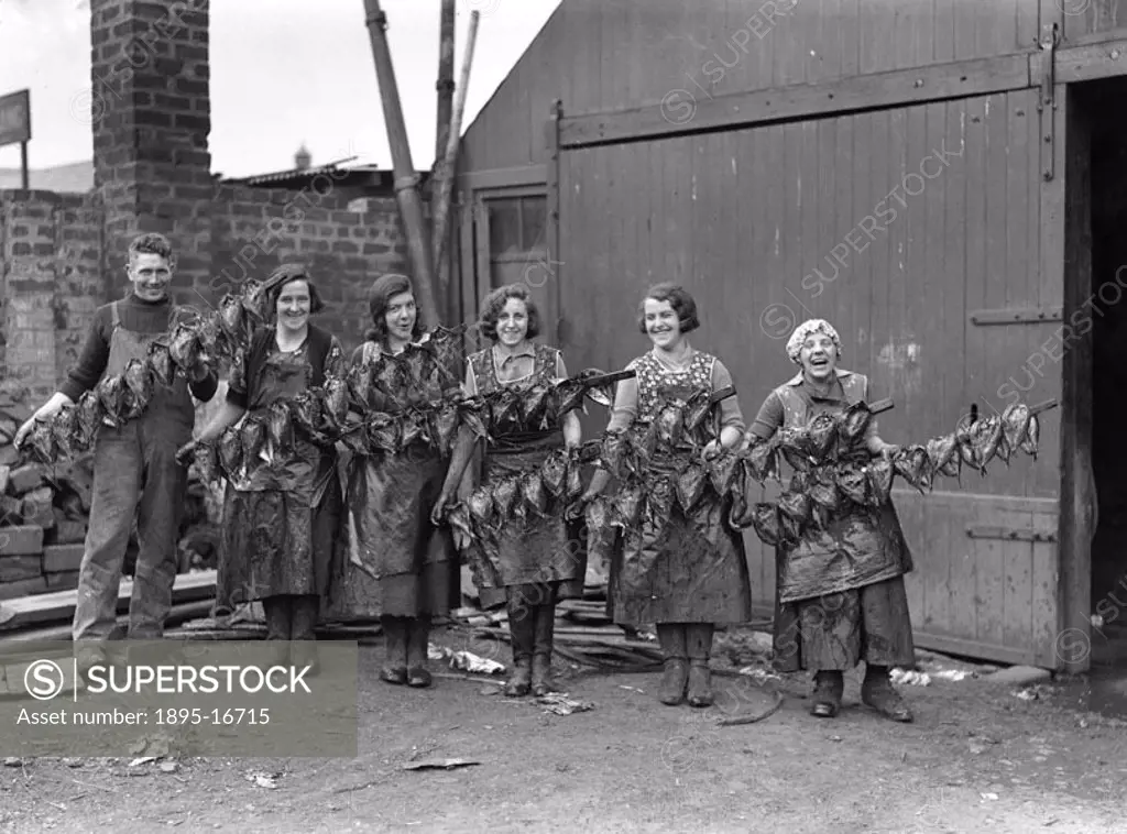Kipper girls displaying smoked kippers, Newhaven, Edinburgh, Scotland, 24 September 1931. This photograph was taken for a series of articles called ´I...