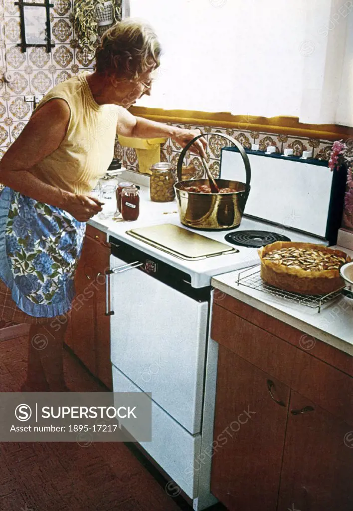 Promotional material for electric cookers showing a woman heating fruit over a hot stove to make jam. On the kitchen top beside the oven a recently ba...
