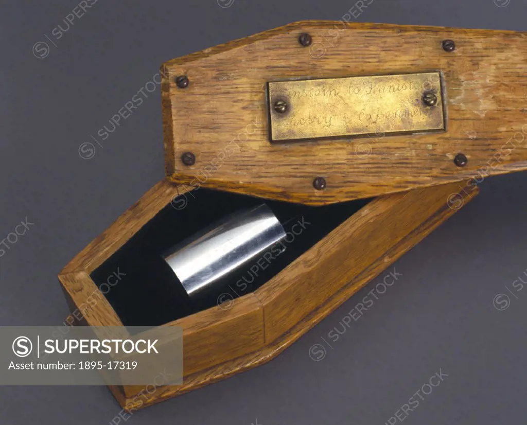 Metal cylinder in a coffin-shaped oak container, presented to Sir Monty Finniston. This object was purchased at a Bonhams Auction in aid of the Britis...