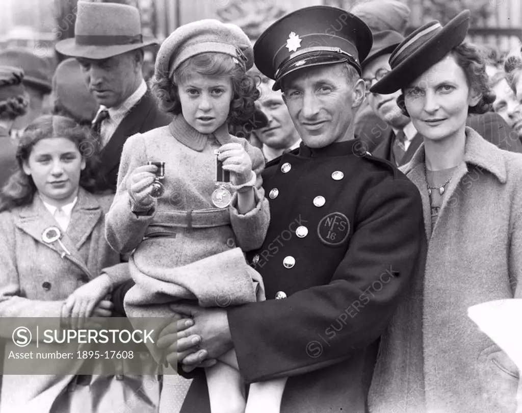 A firefighter and his family outside Buckingham Palace after a medals presentation on Victory in Europe Day at the end of the Second World War  Photog...