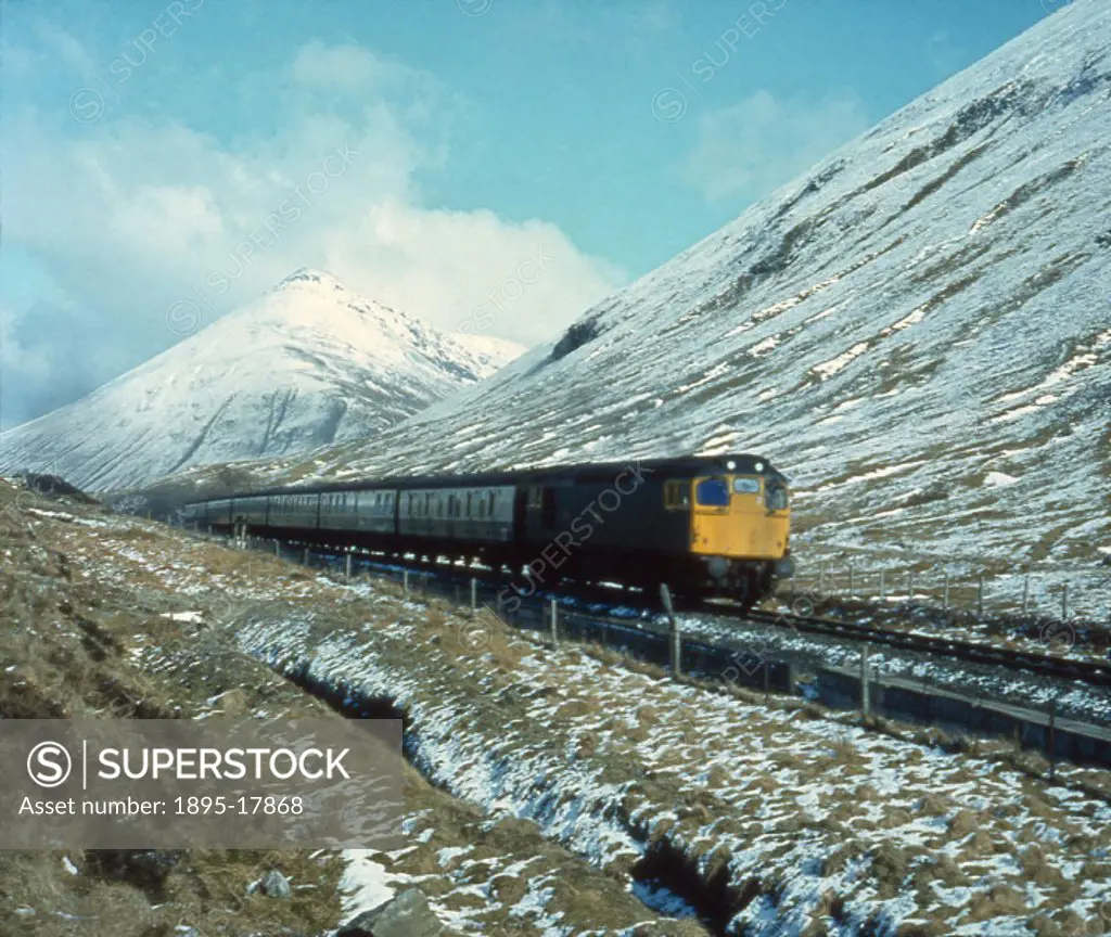 Photograph by Bishop Eric Treacy. Against a backdrop of the conical peak of Ben Doran, Argyll, a Class 27 diesel-electric locomotive heads a Fort Will...