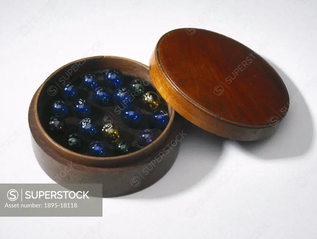 A round mahogany box containing 18 coloured glass bubbles for proof spirits. Made by A Maroni, 34 Brunswick Place, London.