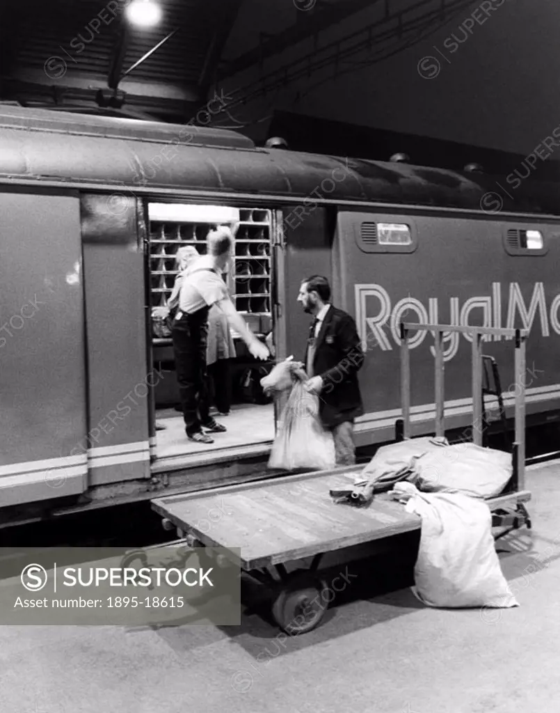 Railway workers load sacks of mail onto the Royal Mail Travelling Post Office sorting van.