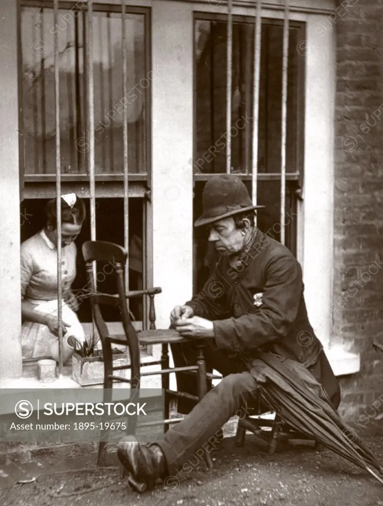 Plate produced using the Woodburytype process of a street performer mending a chair in the street, taken from ´Street Life in London´ (London, 1877) w...