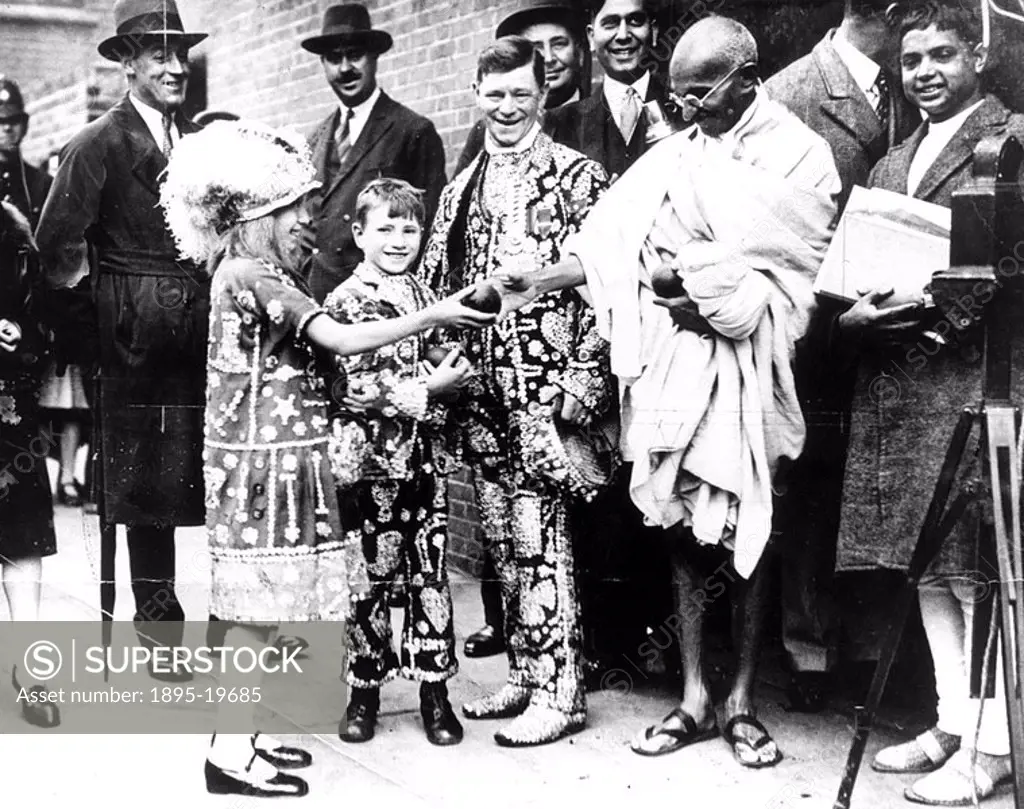 Mahatma Gandhi taking an apple from the daughter of a pearly king  Gandhi 1869-1948 is remembered for his civil disobedience policy against British ru...