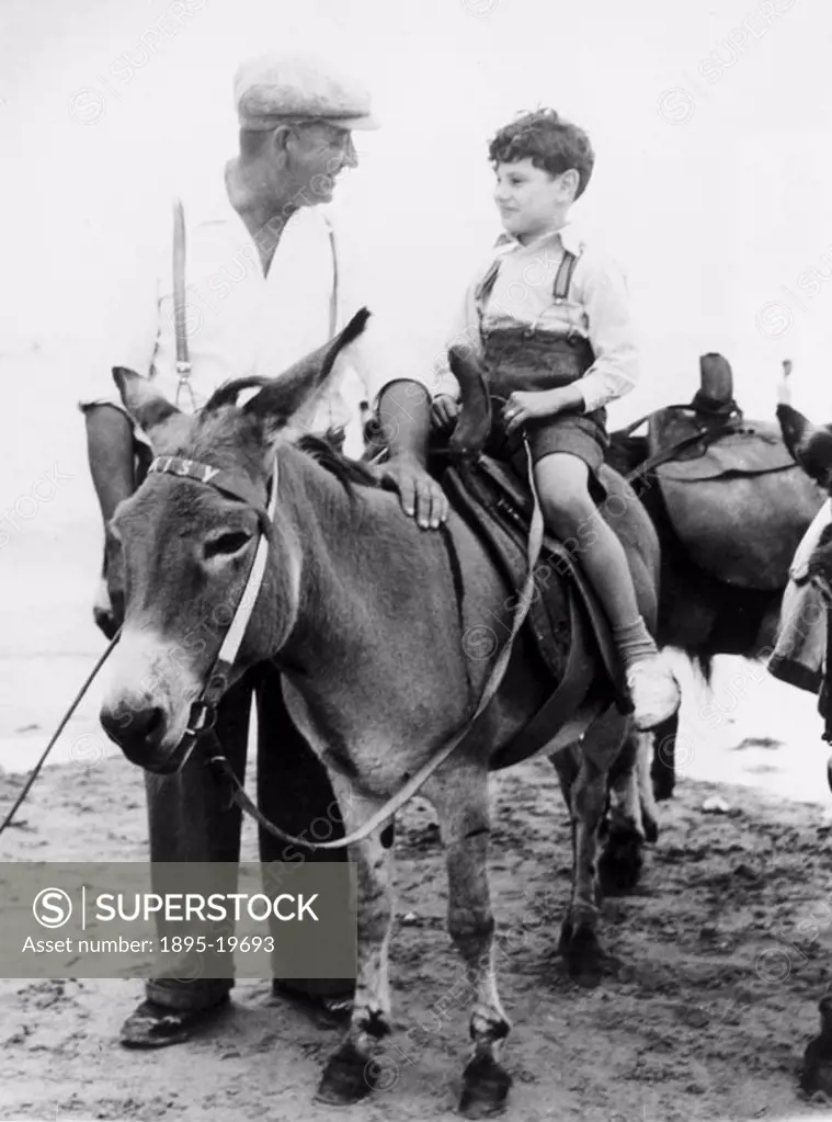 ´Uncle Jack Brown, who for thirty years has been with the donkeys at Margate, gives seven-year-old Jack Joseph of Clapton a ride.´