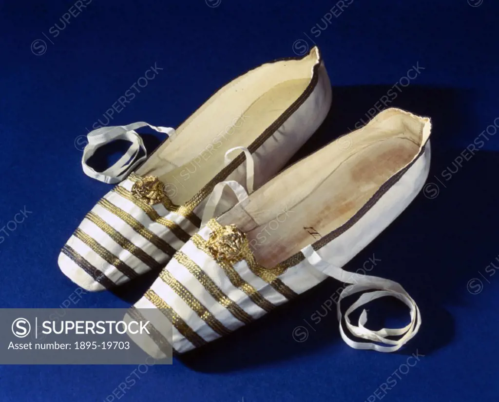 A pair of Queen Victoria´s slippers, made of satin and leather and decorated with stripes of gold braid and gold rosettes, with a pair of white ribbon...