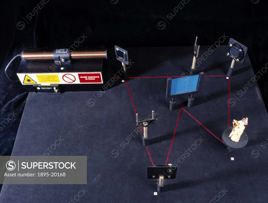This table set up with holography apparatus shows the path a laser beam takes when a holographic image is created. Transmission holograms are created ...