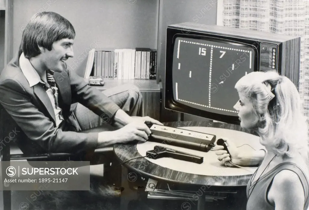 Photograph showing Liverpool FC and England footballer Steve Heighway and a woman playing the computer tennis game Pong on the Videomaster games conso...