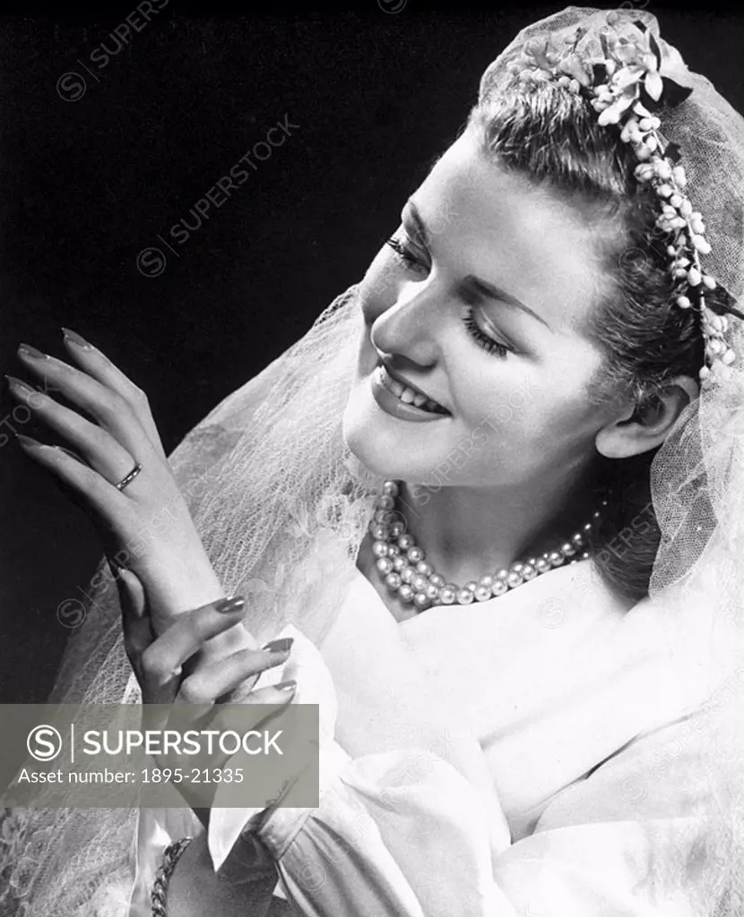 Bride admiring her wedding ring, 1940s Woman wearing a bridal dress looking at her ring