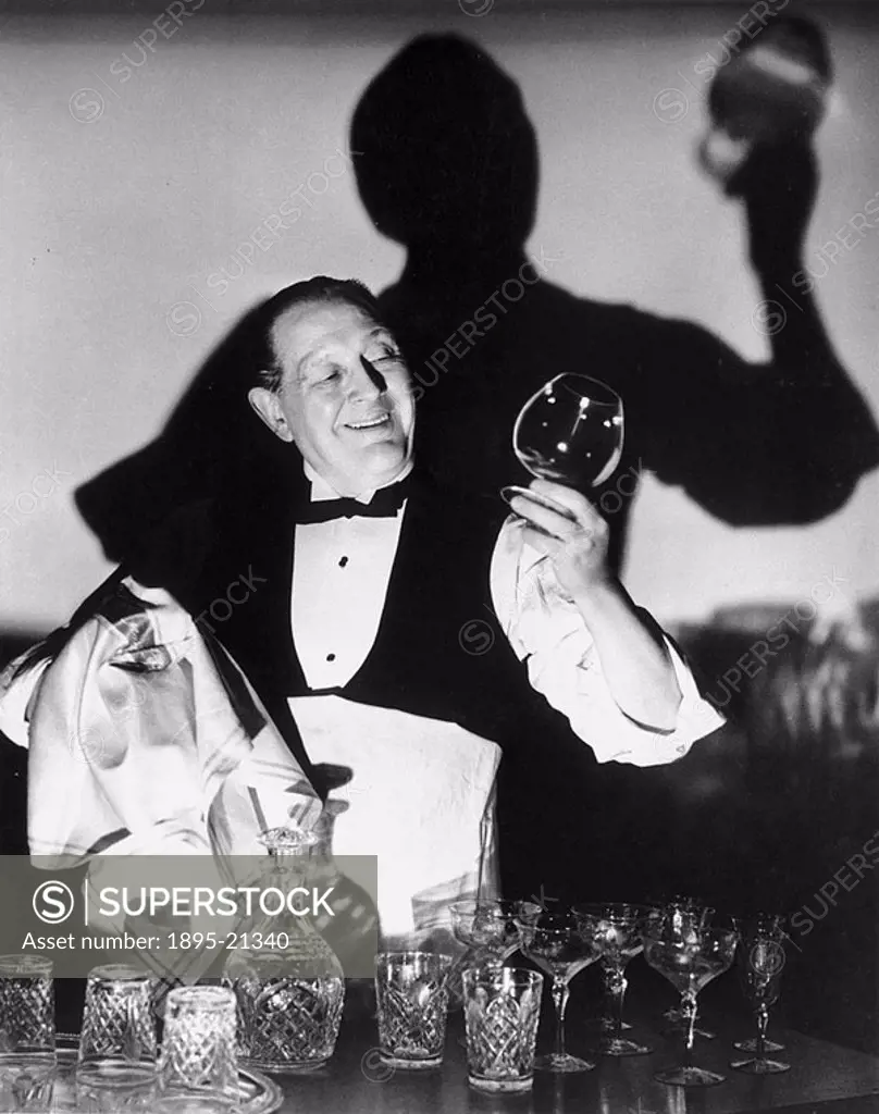 Waiter cleaning glasses, 1940s Hotel waiter admiring his cleaning of a brandy glass