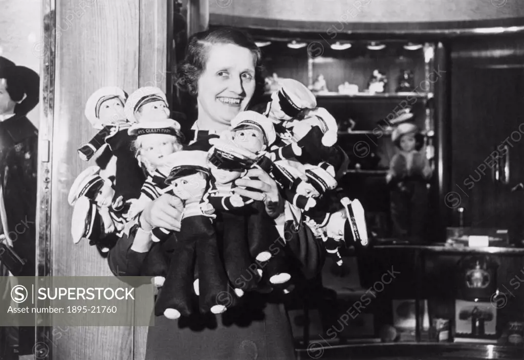 Photograph by Edward G Malindine, showing Edith Beggs, who was in charge of the shopping counter aboard the Queen Mary, holding Queen Mary mascot doll...