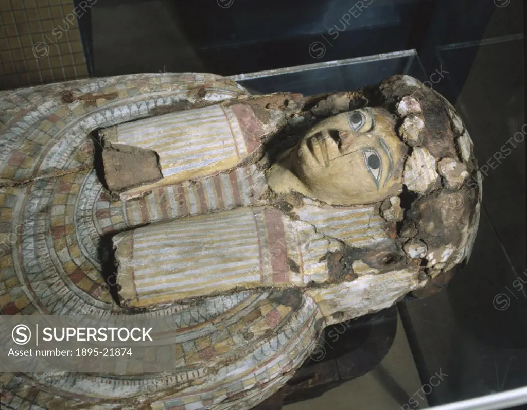 Egyptian mummy of the Hellenistic period in a wooden sarcophagus, shown at the Science Museum, London. The mask over the head and shoulders of the mum...
