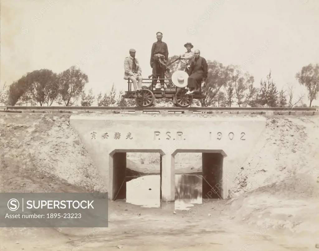 Photograph showing four men on top of a small railway bridge in China, constructed in 1902.