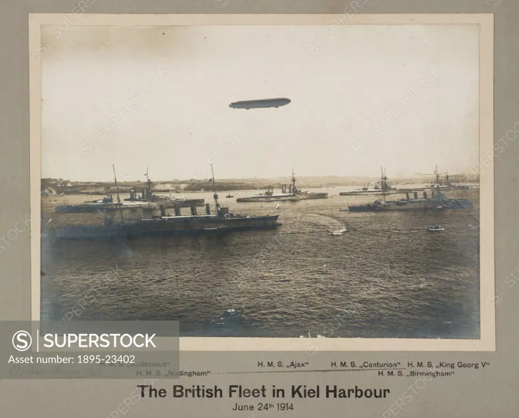Photograph by Arthur George Gill depicting various warships of the Royal Navy on a visit to Kiel Harbour, with a Zeppelin airship flying overhead. The...