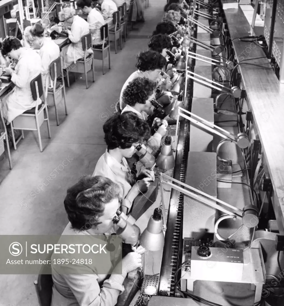 Female employees using microscopes to view transistors on the OC81 line at the Southampton factory of Mullard Electronics. Photograph by Walter Nurnbe...