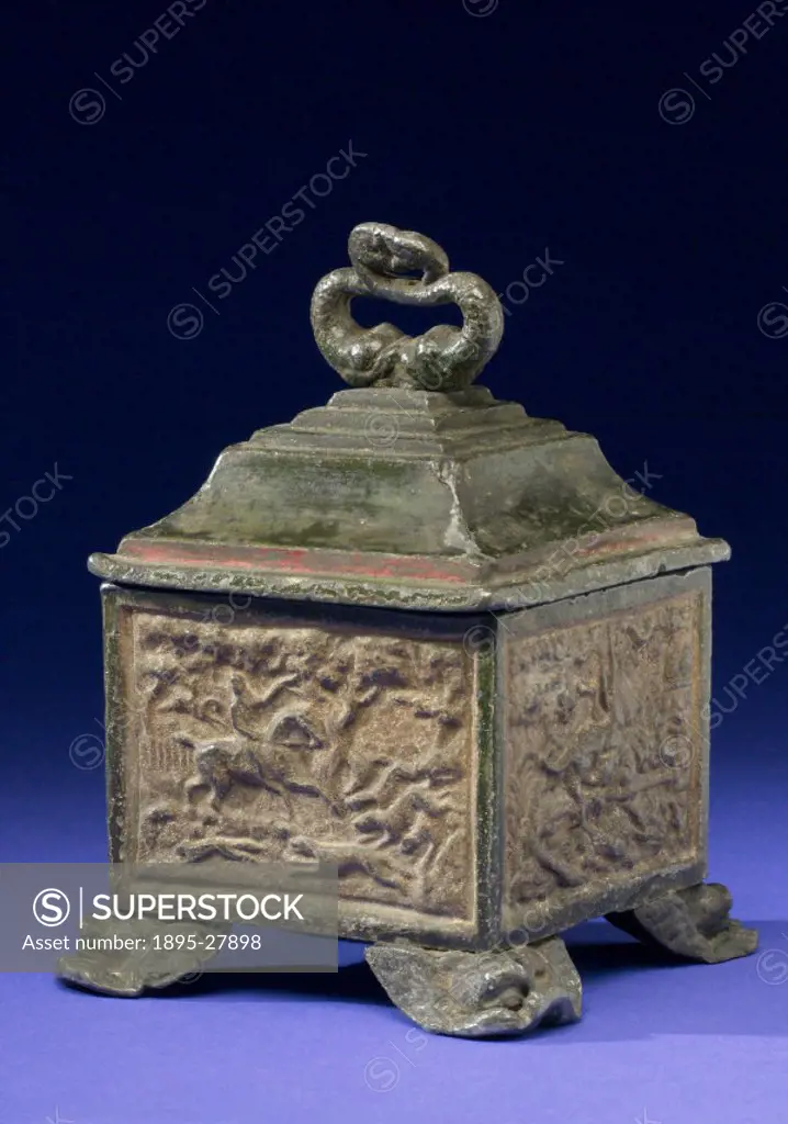Square jar used for storing pipe tobacco resting on rococo type feet and surmounted by a five-tiered lid with torc shaped finial and hunting scenes mo...